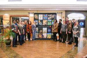 Illustration students pose with proposed cover images at Garden Spot Village.