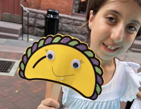 young girl holding empanada-shaped maraca