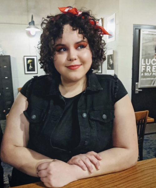 curly haired woman in a dark shirt looking to her left off camera.