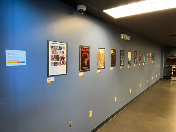 lineup of student-designed movie posters hanging on a dark gray wall.