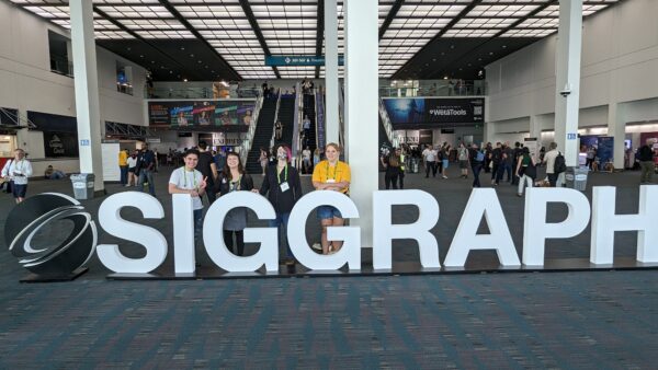 four people lined up behind a 3D sign that reads SIGGRAPH