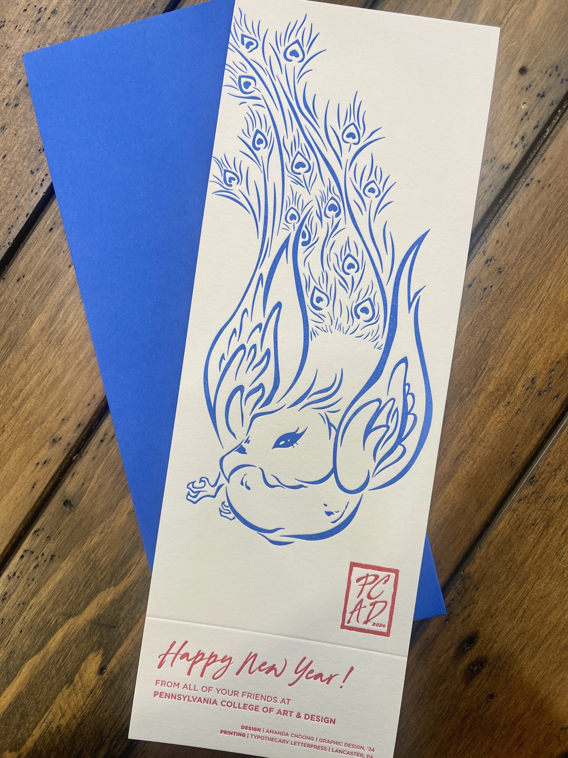 Vertical white New Year's greeting card with image of blue peacock and red text.