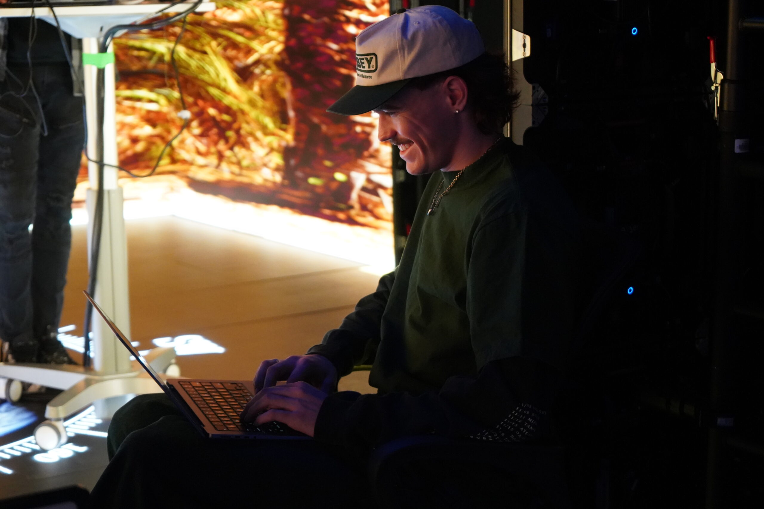 Smiling student wearing baseball capworks on programming a final project. 