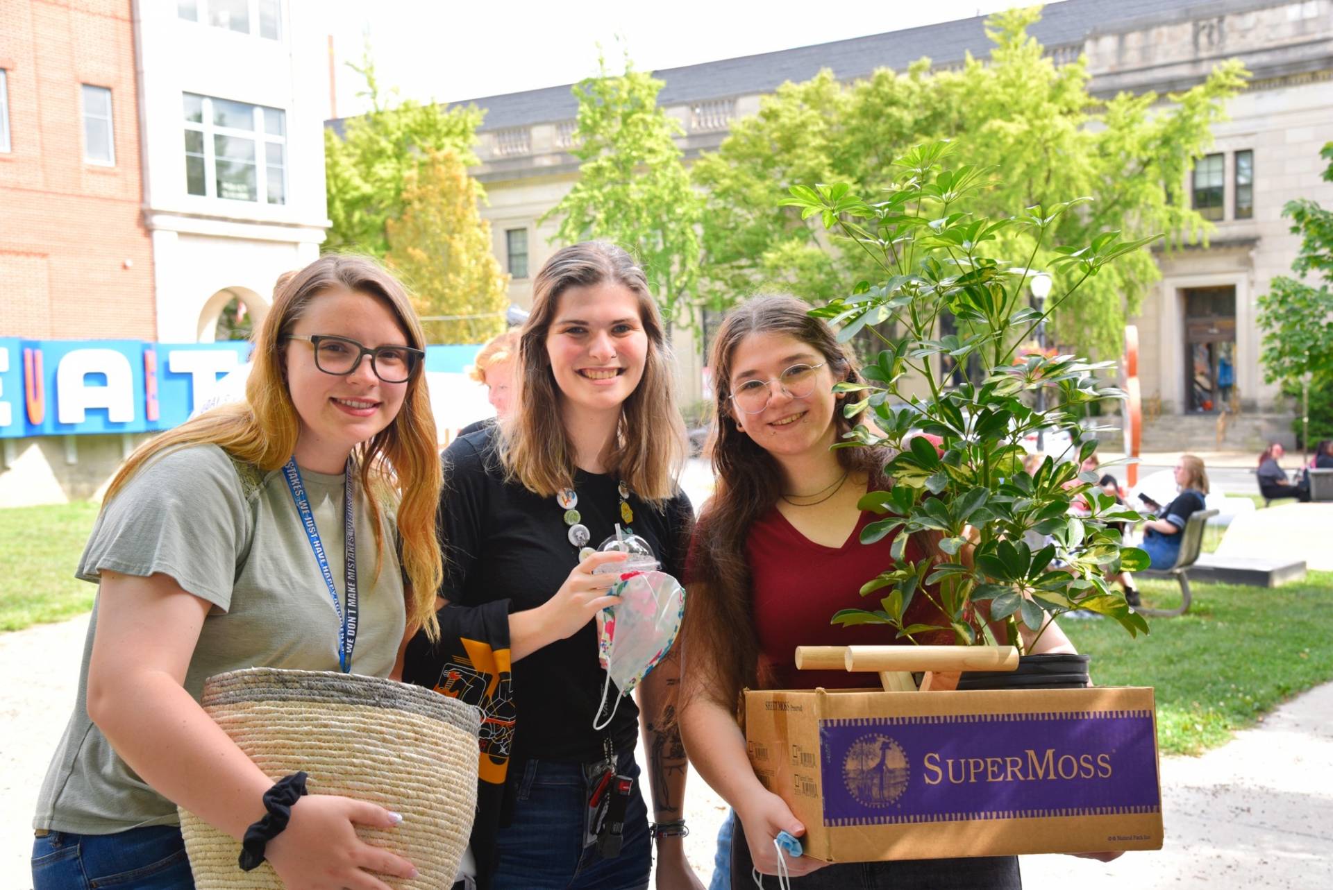 Three students pose in hte Art Garden with their new plant. 
